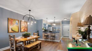 A spacious kitchen with wooden flooring, a dining area with rustic chairs, and a bar area with a foosball table.