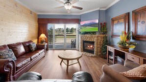 A cozy living room with a fireplace, a leather sofa, a round coffee table, and a stone fireplace surround.