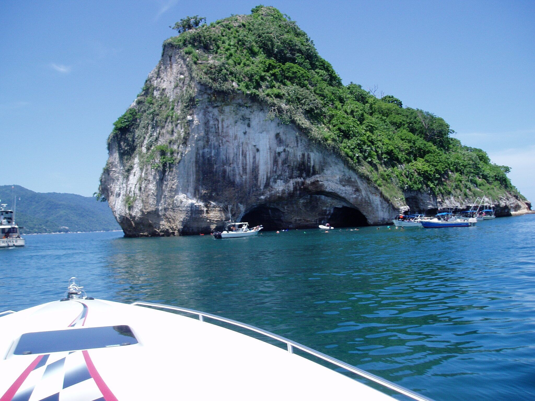 A boat near a large rock formation surrounded by water.
