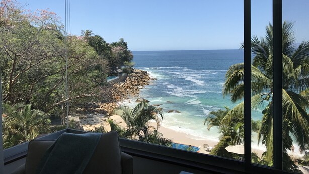 A room with a large window overlooking a beach and ocean.