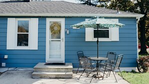 Una casa blu con veranda, un tavolo e sedie, e un ombrello decorato.