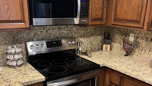 A kitchen with wooden cabinets, a stainless steel microwave, a stove, and a sink. - Absolutely Pristine 2-2 Lower Unit with Stunning Views! 2027 BNP Paribas Close!! (La Quinta)