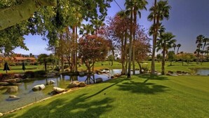 A well-maintained golf course with a pond, palm trees, and a clear sky. - Absolutely Pristine 2-2 Lower Unit with Stunning Views! 2027 BNP Paribas Close!! (La Quinta)