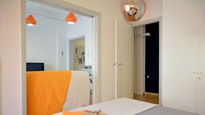 Ein Schlafzimmer mit Bett, Nachttisch, Spiegel und einer Tür zu einem anderen Raum.