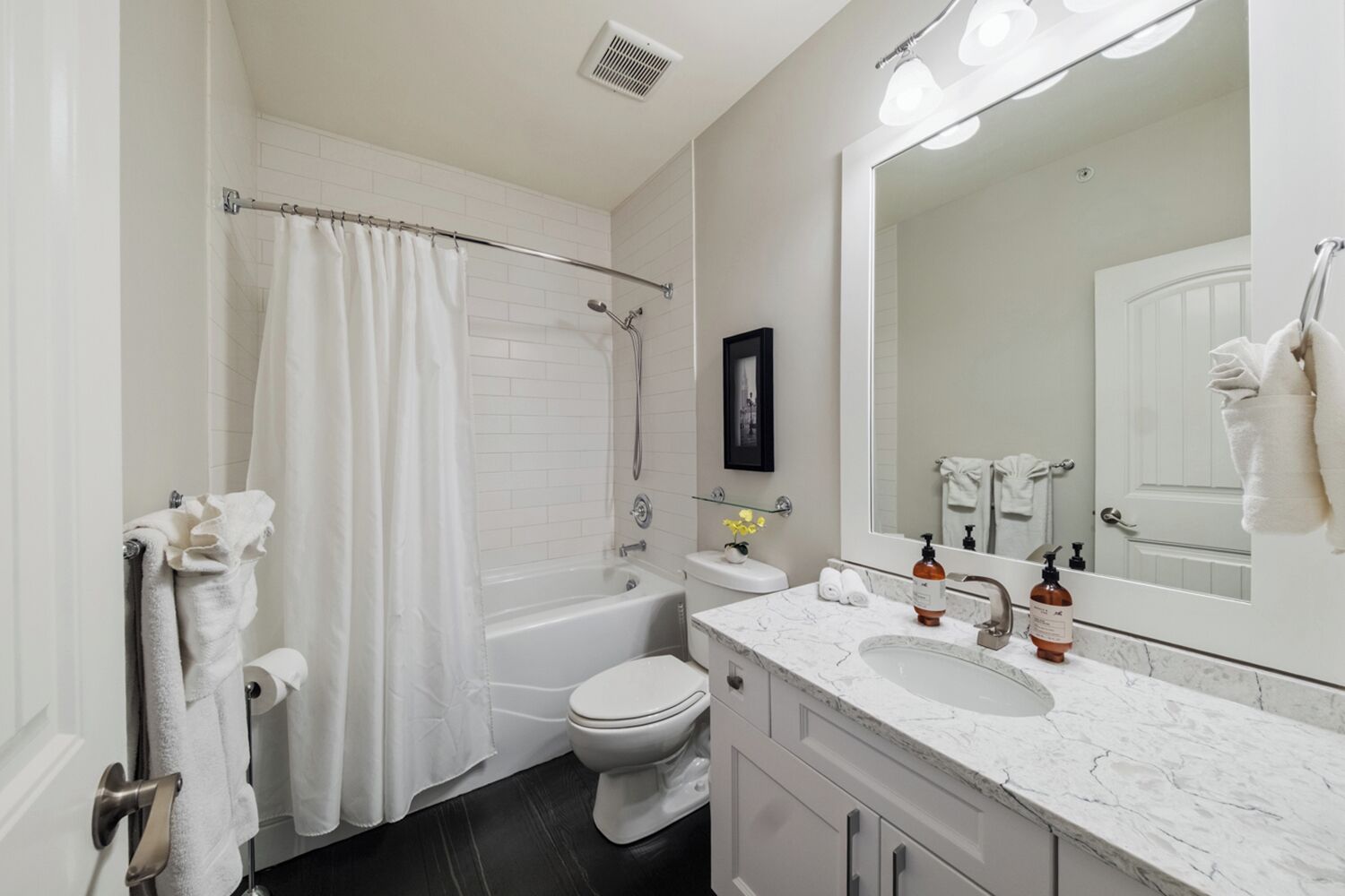 A bathroom with a bathtub, toilet, and a large mirror.