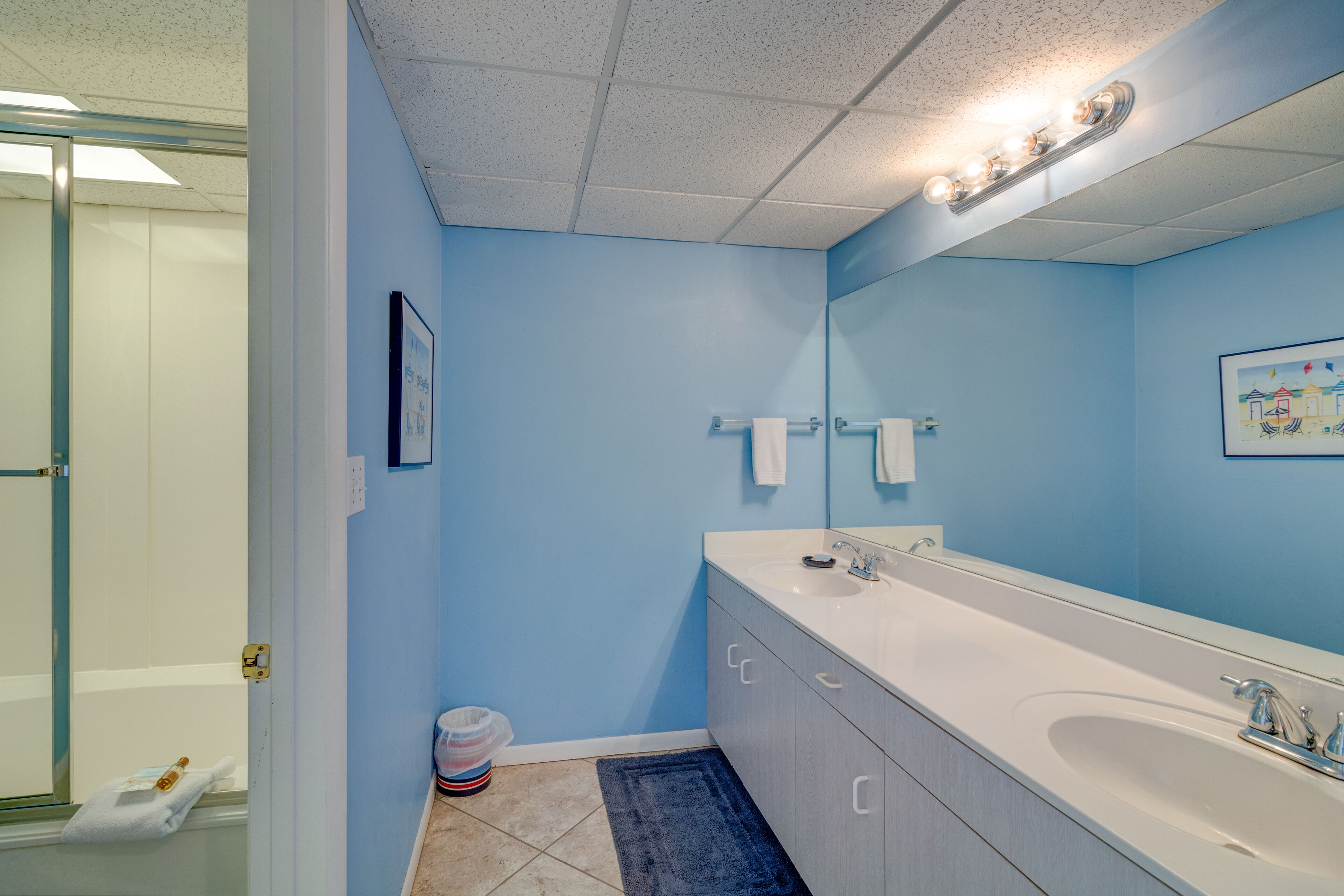 Un baño con un lavamanos blanco, un espejo grande y paredes azules.