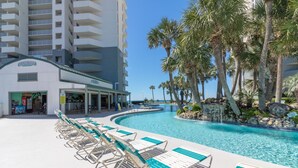 A pool area with lounge chairs and a building with a sign that reads "HANGOUT."