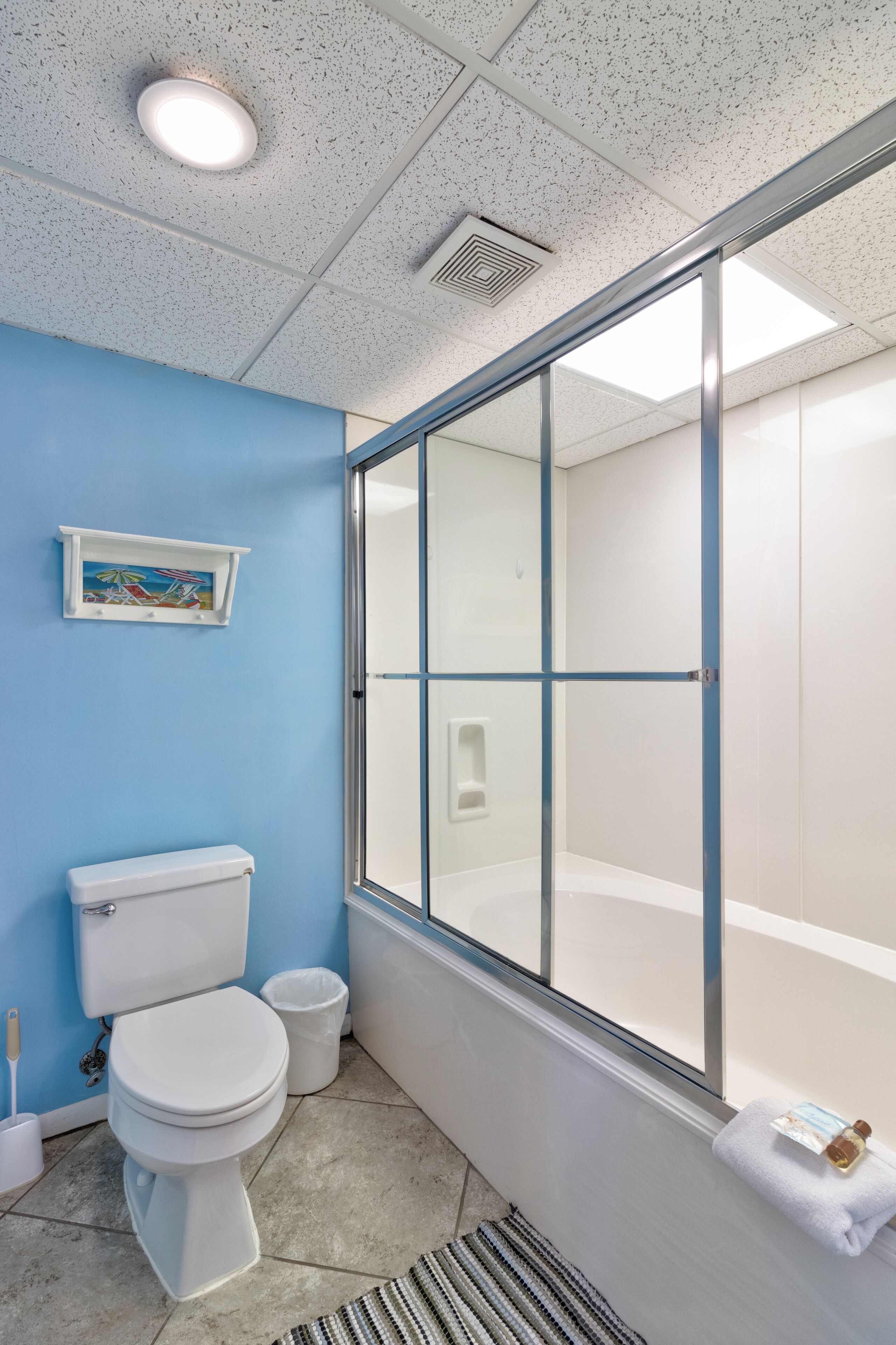 Un baño con inodoro, lavamanos y ducha con mampara de vidrio.