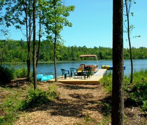 Relax on the lakeside dock, surrounded by lush greenery and trees, perfect for a peaceful retreat.