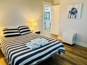 Un lit bien fait, avec une literie à rayures, une lampe de chevet et une serviette pliée posée sur le lit.