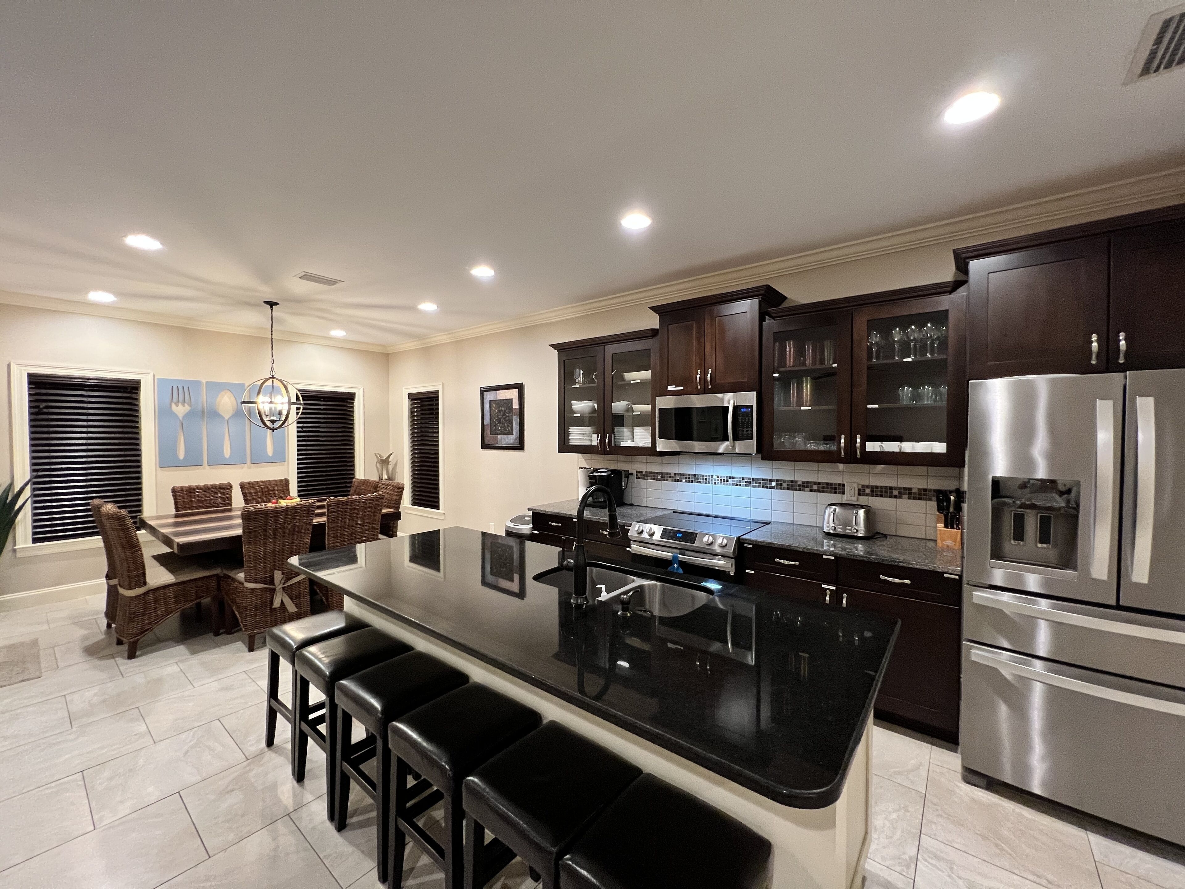 A modern kitchen with dark wooden cabinets, stainless steel appliances, and a central island with bar stools.
