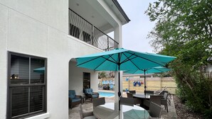 Un espace extérieur aménagé avec des meubles en osier, une table en verre et un grand parasol.