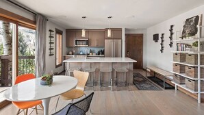 A modern kitchen with a central island, bar stools, and a dining table with chairs. - Minutes to festivals - Pool, Jacuzzi, Fitness room (Snowmass Village)
