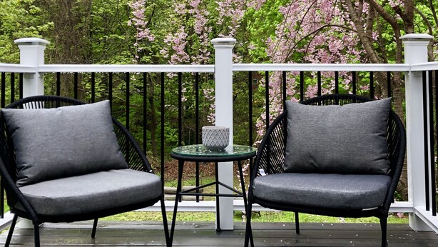 A wooden deck with two black wicker chairs and a small round table with a white vase. - In town, newly remodeled studio with private balcony  (Shelburne Falls)
