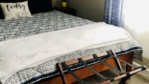 A neatly made bed with a patterned bedspread, a pillow with text, a bedside lamp, and a wooden floor. - In town, newly remodeled studio with private balcony  (Shelburne Falls)
