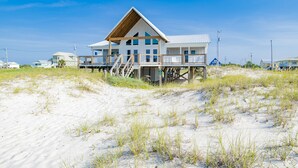 A beachfront house with a wooden deck and multiple levels, surrounded by sand dunes. - Amazing Views! Beachfront Home Sleeps 16-Private Pool & Private Beach! (Gulf Shores)