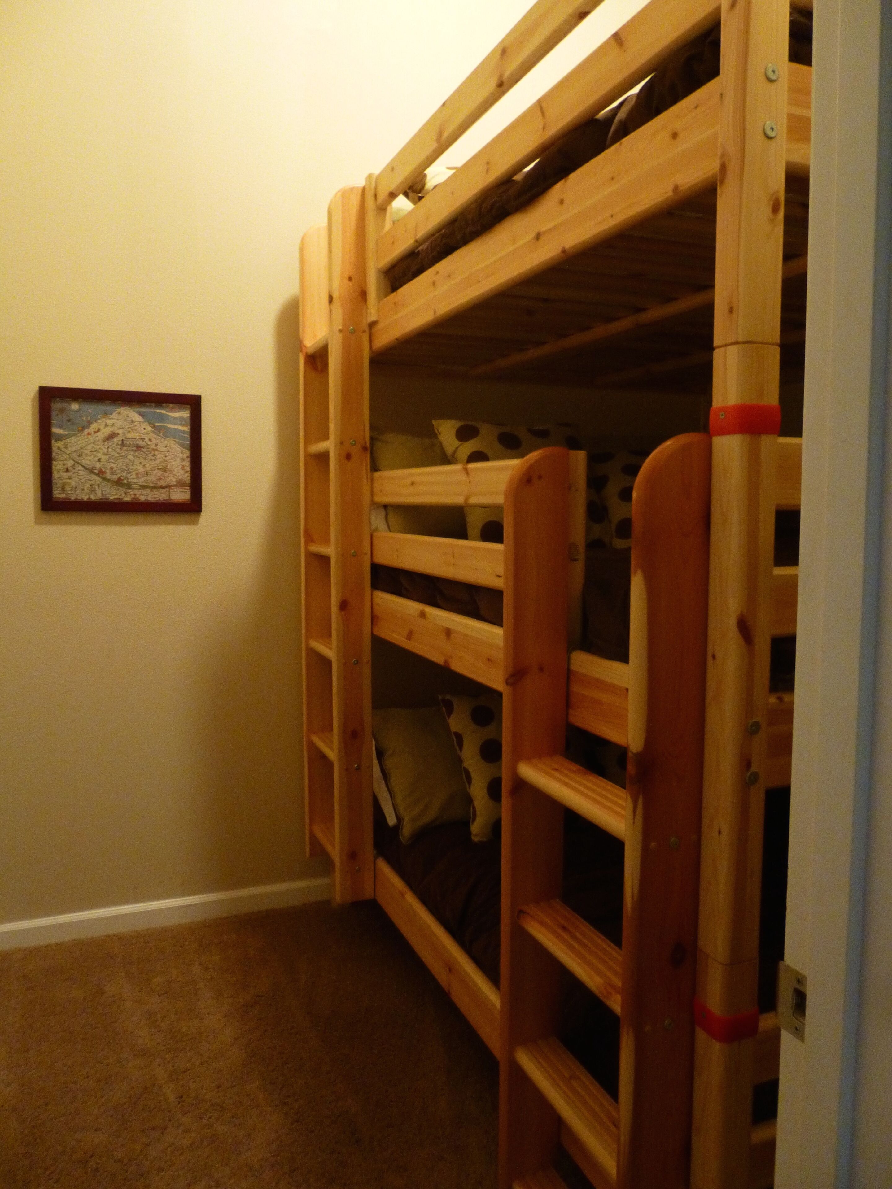 A bunk bed with a ladder, a polka-dotted pillow, and a framed picture on the wall.