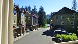 A row of townhouses with a street in between, surrounded by trees and a mountain in the background. - Ideal location in Collins Lake, close to pool with views of Forest & the Slopes (Government Camp)