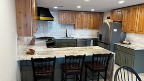 A kitchen with wooden cabinets, a marble countertop, and a stainless steel refrigerator. - MILLION DOLLAR VIEW! 4 Bedrooms all with Private Bathroom, Great Dock 16X36 Slip (Sunrise Beach)