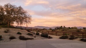 A wooden bridge over a gravel path leading to a scenic overlook with a view of distant mountains and a tree-lined landscape. - MYSTICAL HILLTOP RANCH (Santa Ynez)