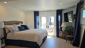 A bedroom with a bed, a desk, a chair, a TV, and a view of the outdoors. - MYSTICAL HILLTOP RANCH (Santa Ynez)