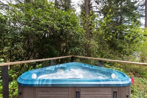 A hot tub with a wooden deck and a MARQUIS logo, surrounded by dense greenery. - Cozy A-Frame w/Spa+14 acres+EV+Trails+Lake Access (Lakeside)