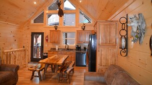 A wooden cabin interior with a dining area, kitchen, and seating. - Luxury 4 King Suites, 4 Bath Log Cabin Close to Town & Trolley (Gatlinburg)