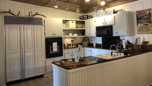 Een keuken met witte kastjes, een zwarte koelkast en een houten aanrecht.