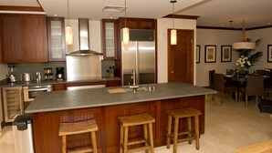 Una cocina moderna con una isla grande, armarios de madera, electrodomésticos de acero inoxidable e iluminación colgante.
