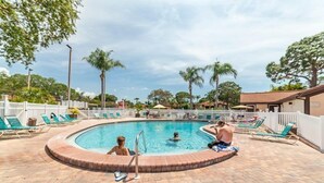 Una piscina circular con sillones de descanso y palmeras al fondo.
