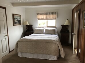 A bedroom with a bed, two bedside tables with lamps, a window with a valance, and a door. - Crows Nest, on the Bluff over Trinidad Bay, amazing views! (Trinidad)