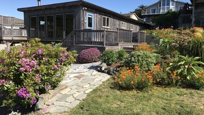 A wooden house with a stone pathway leading to a wooden deck.
