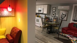 Una sala de estar con un sofá rojo, una pared amarilla y un comedor con una mesa y sillas.