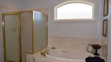 A bathroom with a bathtub, a glass-enclosed shower, and a vanity with a mirror.