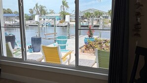 A room with a large window overlooking a marina with boats and a dock. There is a chair and a potted plant inside the room. -  The Crab Shack,Paradise on the Gulf includes pontoon boat  and salt water pool. (New Port Richey)