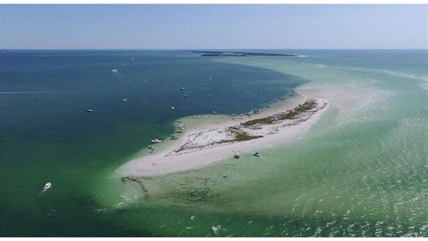 An aerial view of a coastal area with a narrow strip of land, clear waters, and boats. -  The Crab Shack,Paradise on the Gulf includes pontoon boat  and salt water pool. (New Port Richey)