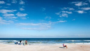 A beach with people and beach chairs, a clear sky, and the ocean. - Wanna Sea #202 - Newly Renovated Balcony! (Fernandina Beach)