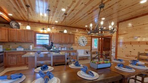 A wooden cabin-style kitchen with a dining area set for a meal. - A Heavenly View ~ 6 BR Indoor Pool Cabin ~ Sleeps 28 ~ Incredible Views! (Sevierville)