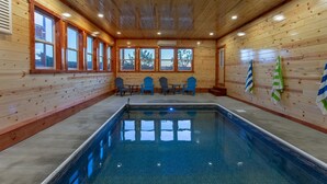 A wooden cabin with a pool, three chairs, and a table. - A Heavenly View ~ 6 BR Indoor Pool Cabin ~ Sleeps 28 ~ Incredible Views! (Sevierville)