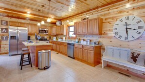 A spacious kitchen with wooden cabinets, a stainless steel refrigerator, a microwave, and a large wall clock. - A Heavenly View ~ 6 BR Indoor Pool Cabin ~ Sleeps 28 ~ Incredible Views! (Sevierville)