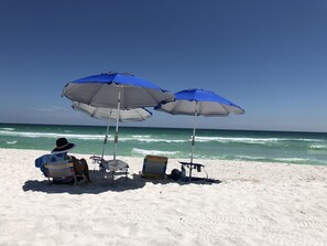 A beach scene with two umbrellas and beach chairs. - Private Home! Corner Lot steps from the Beach! One minute walk to the beach.
(Pensacola Beach)
