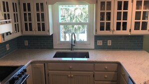 Una cocina con ventana, armarios, un lavabo y una estufa.
