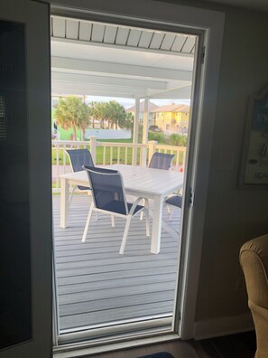 Et værelse med en skydedør, der fører ud til en udendørs terrasse med et bord og stole.