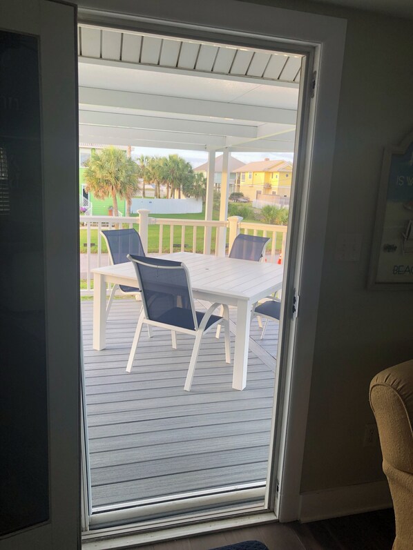 A room with a sliding glass door leading to an outdoor patio area with a table and chairs. - Private Home! Corner Lot steps from the Beach! One minute walk to the beach.
(Pensacola Beach)