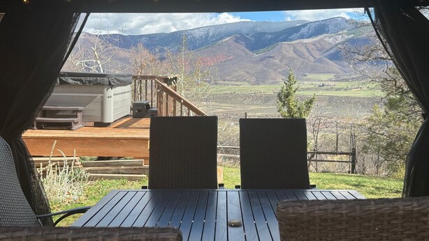 Une terrasse avec une table et des chaises, offrant une vue sur un paysage montagneux.