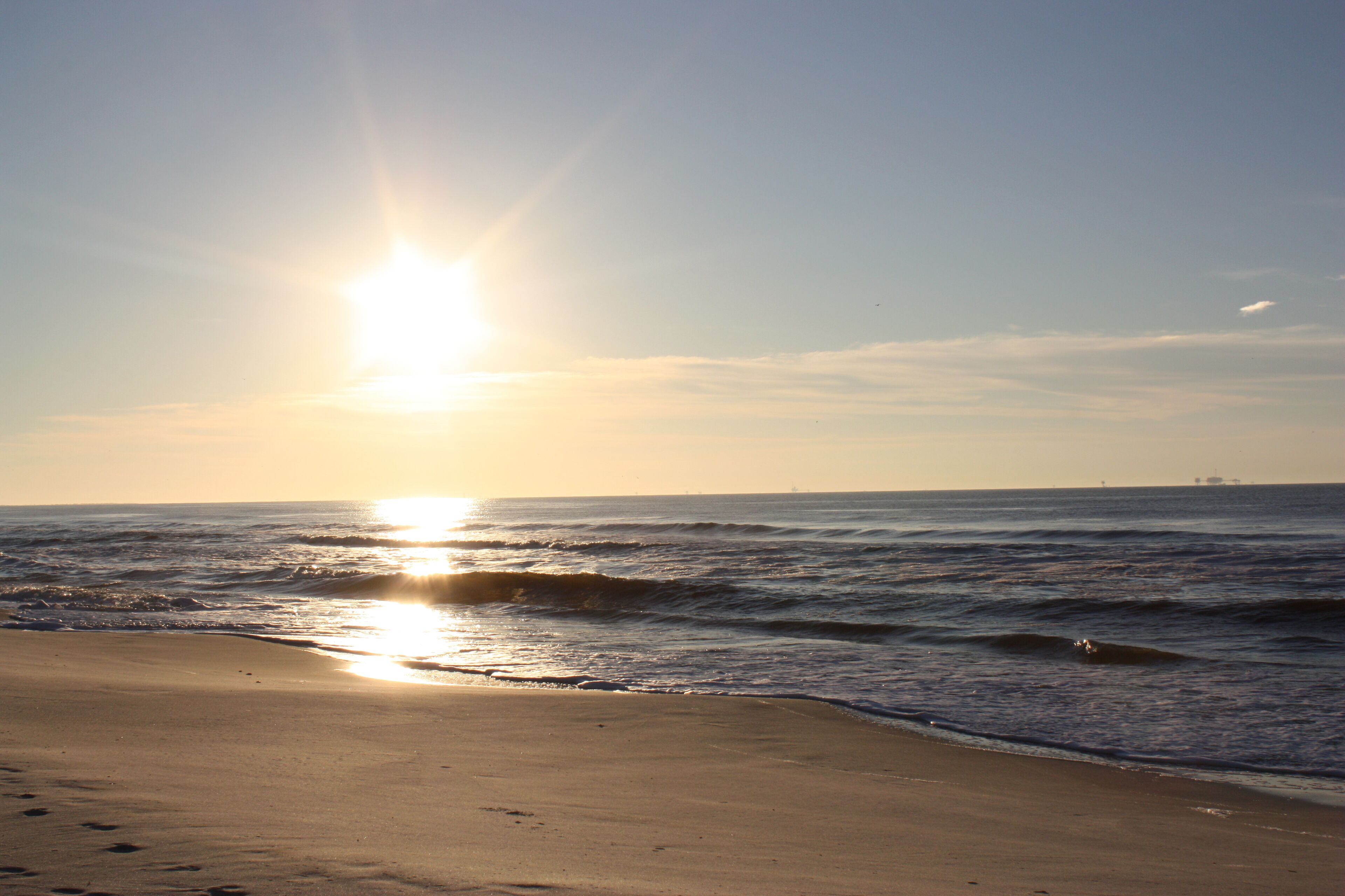 Une plage où le soleil se couche sur l’océan, créant une atmosphère paisible.