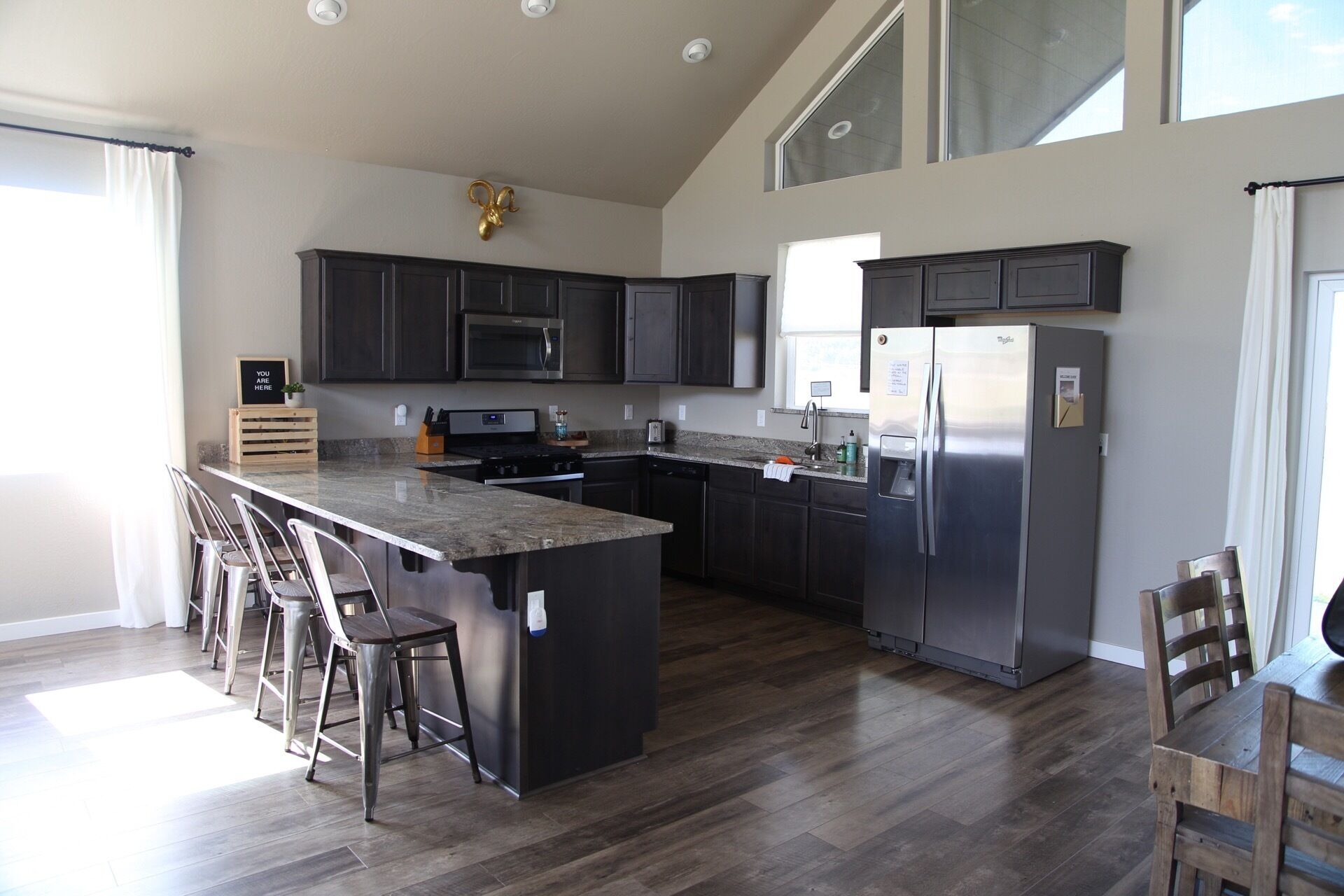 A modern kitchen with dark cabinets, stainless steel appliances, and a large island with bar stools.