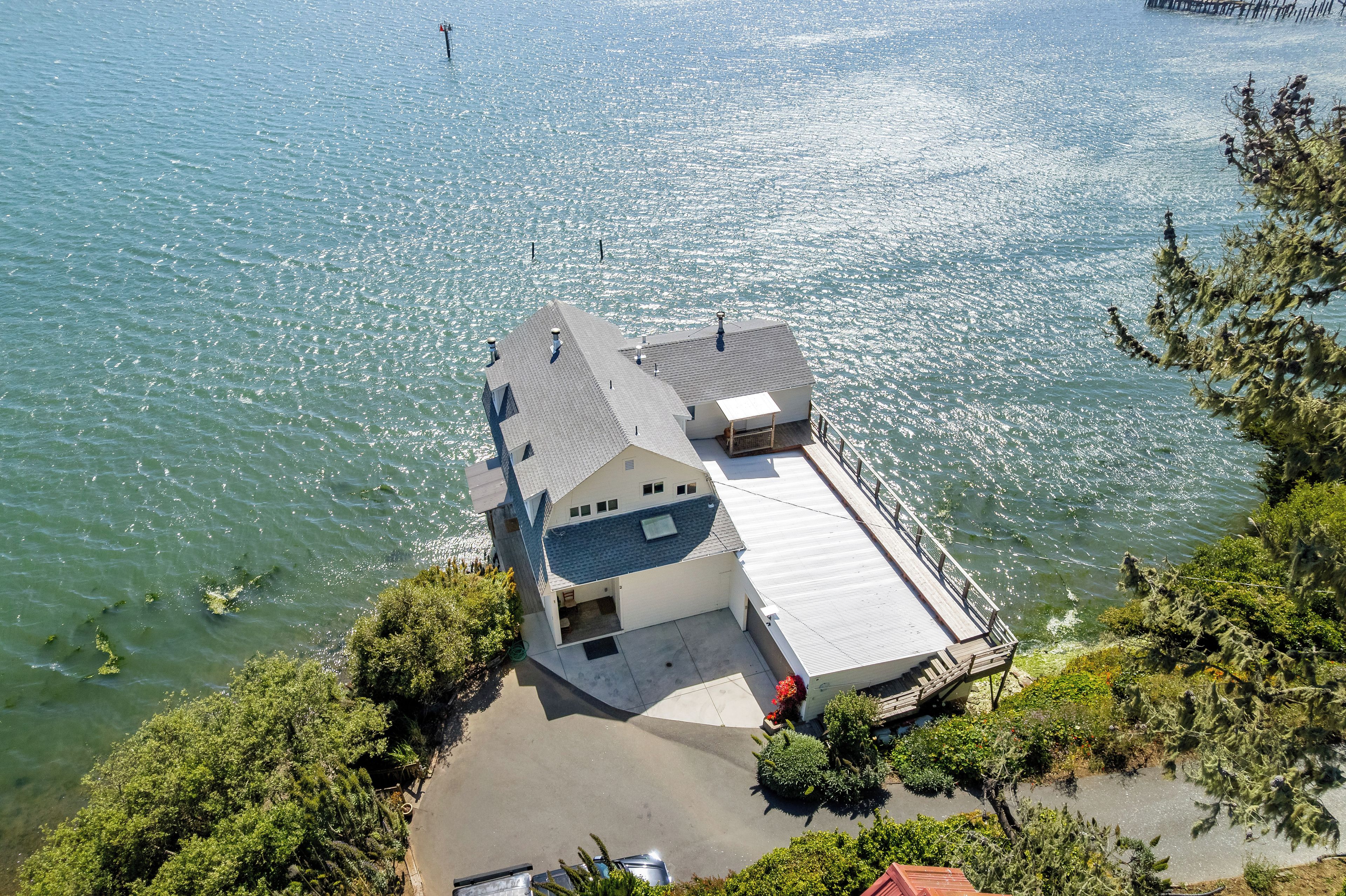 A house with a sloped roof, a covered porch, and a view of the water.