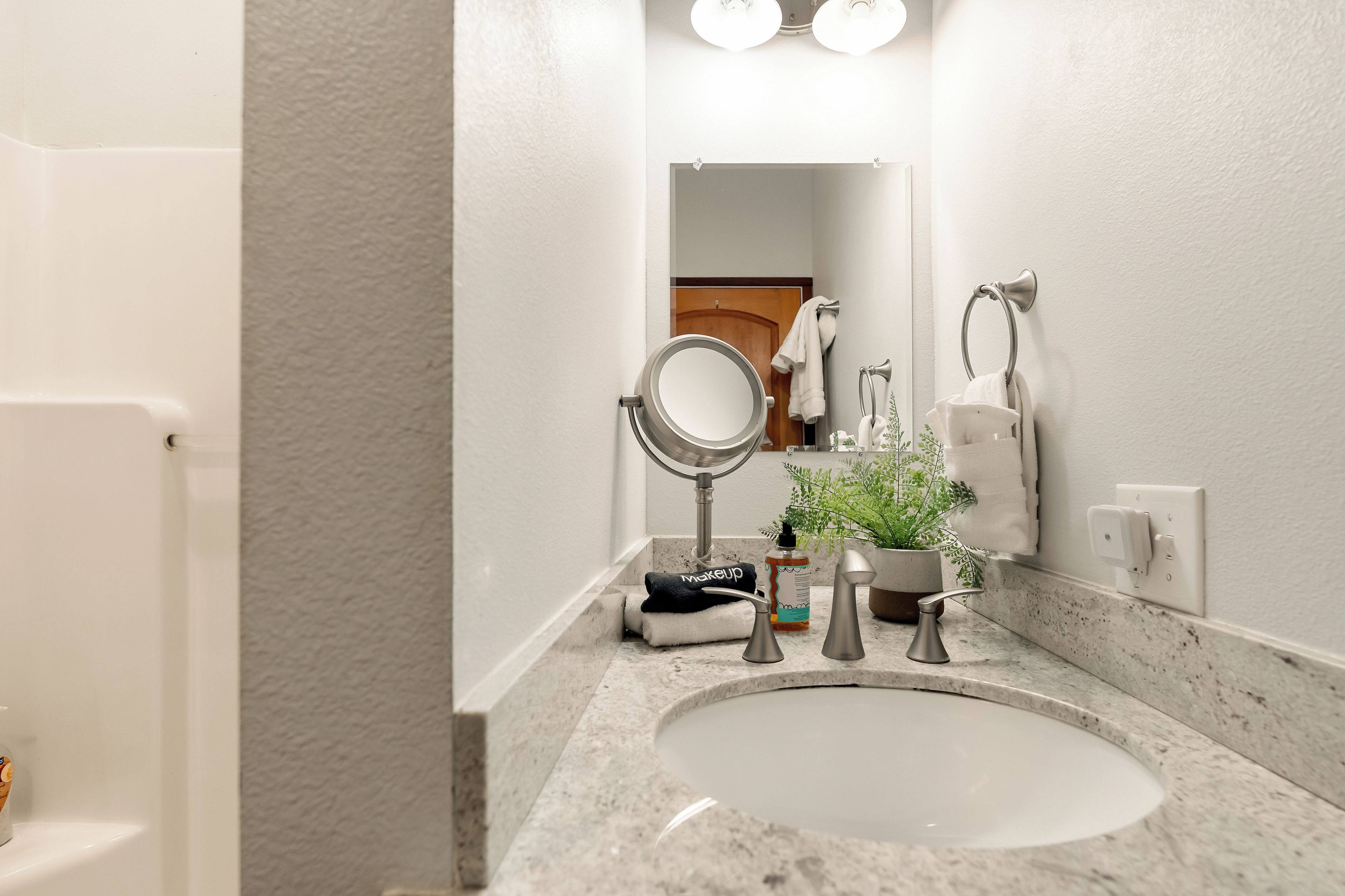 A bathroom with a sink, mirror, towel rack, and a potted plant.
