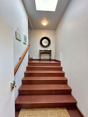 A staircase with a wooden handrail leading to a landing with a round mirror and a small table. - Waterfront 2 Bed-King/Queen , 2 Bath + INCREDIBLE VIEWS perched  over Bodega Bay (Bodega Bay)
